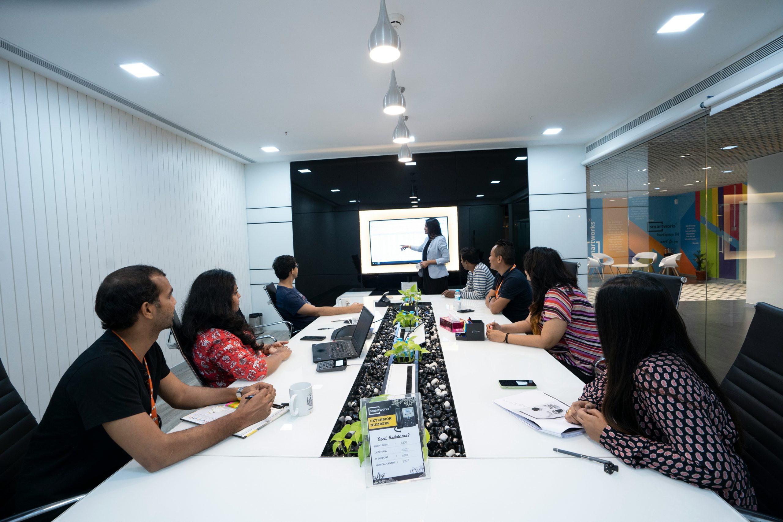 "Team discussing strategies in a modern meeting room with a professional presentation at Digital Decimal."